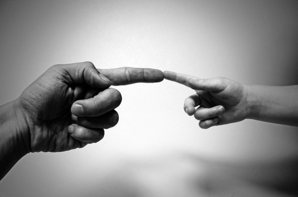 Charitable giving what to do before you donate depicts a man and child touching fingers.