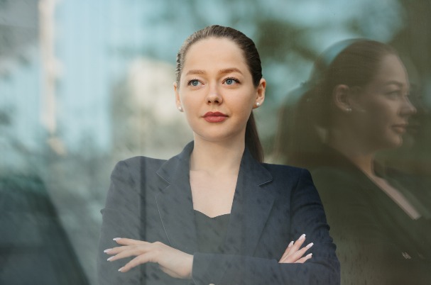 Is it Worth the Money to Hire a Financial Advisor? A female advisor in a navy blue blazer is leaning against the glass wall in the financial district.