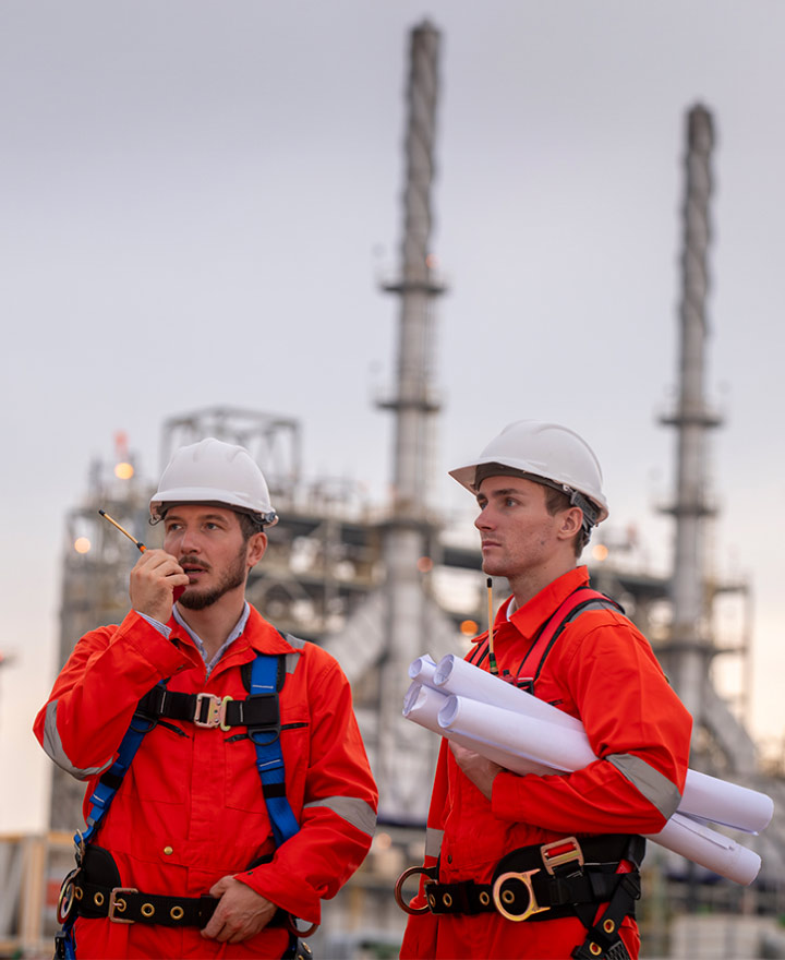 Financial planning for oil and gas professionals photo concept with engineer team wearing coveralls and helmets surveying oil field site.