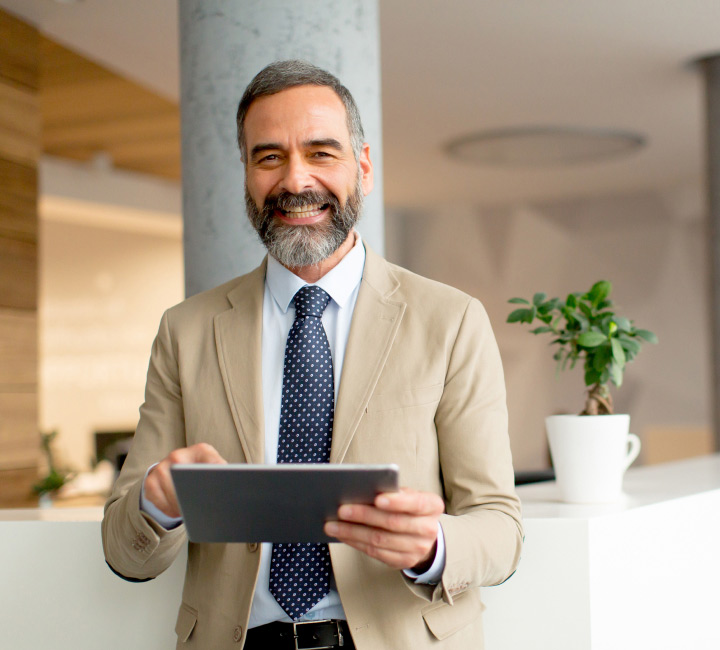 Financial planning for tech professionals concept with mature businessman holding digital tablet in the office.