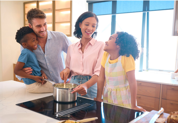 Next generation financial planning photo concept with happy multi-racial family cooking together in the kitchen.