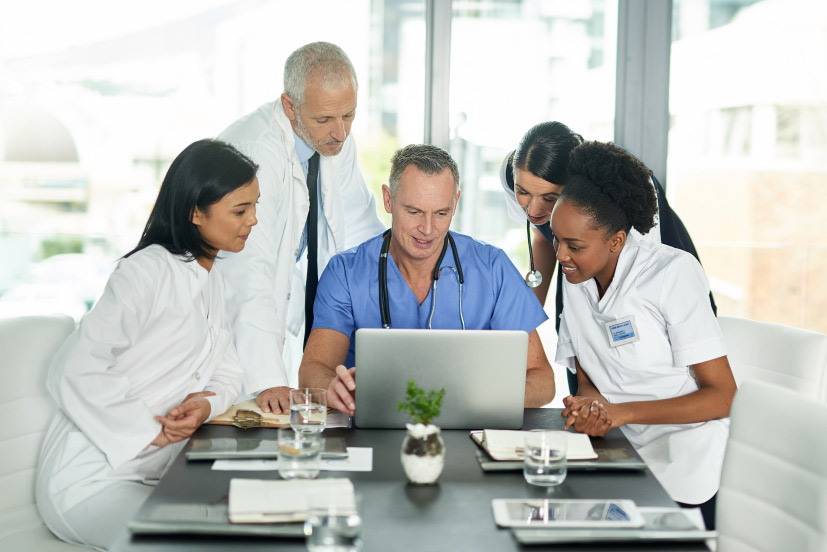 Healthcare providers portrait of doctors in hospital hovering over a laptop.