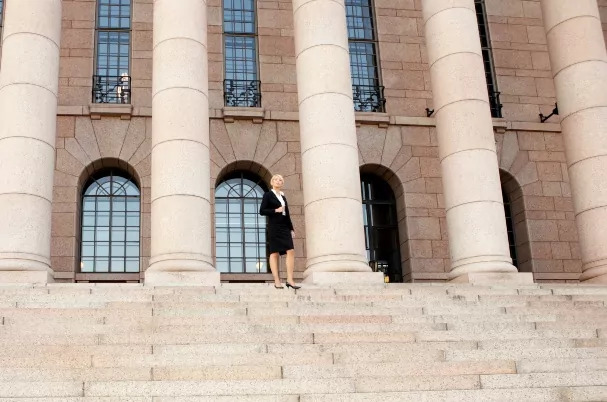 Seven Pillars of Financial Success concept photo with woman standing at the top of steps next to grand pillars.