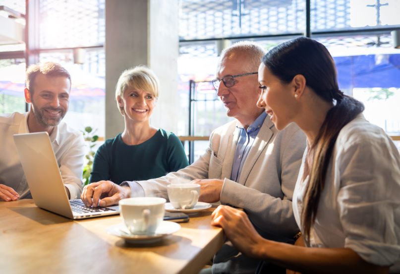 Selecting an employee retirement plan management solution concept with four people reviewing a computer.