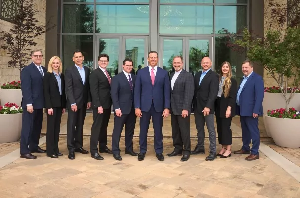 Global Wealth Advisors (GWA) team standing in front of a glass door and surrounded by flower pots.