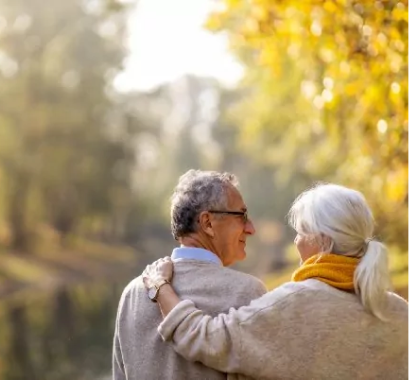 Preventing elder fraud concept image of an elderly man and woman walking close together in the park.