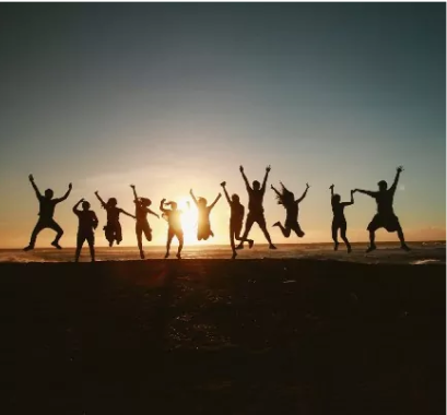 Guide To charitable giving concept of multiple people jumping in the air in celebration silhouetted in front of the setting sun.