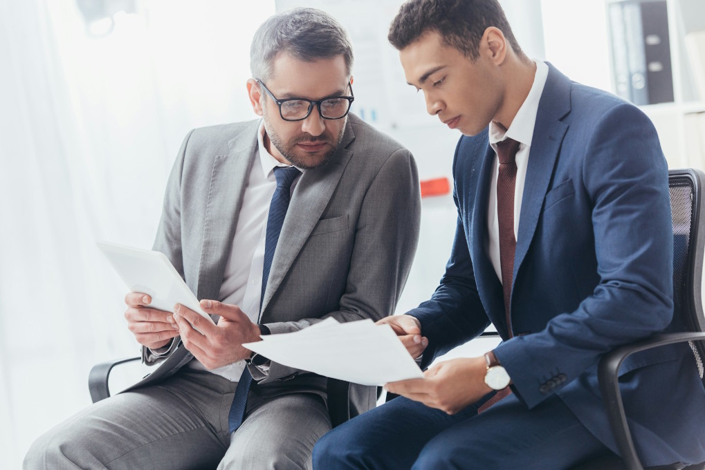 About us shows a photo of two men looking over paperwork.