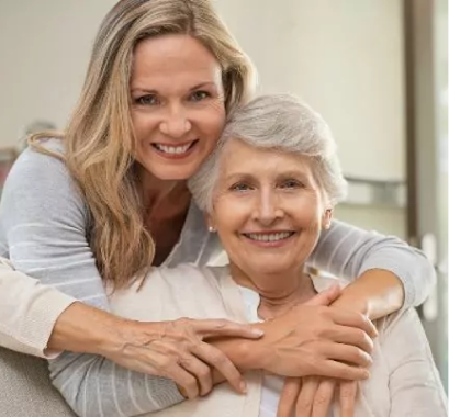 Enrolling In Medicare concept with a young woman hugging an older seated woman from behind.