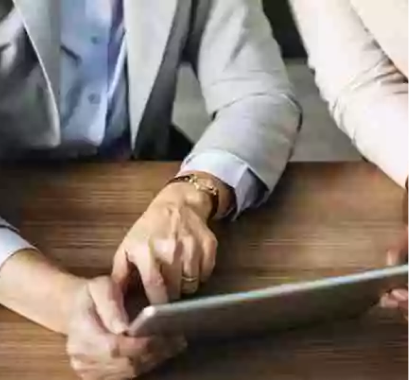 Social Security and Medicare guide concept of a woman showing a man how to fill out a form on her tablet.